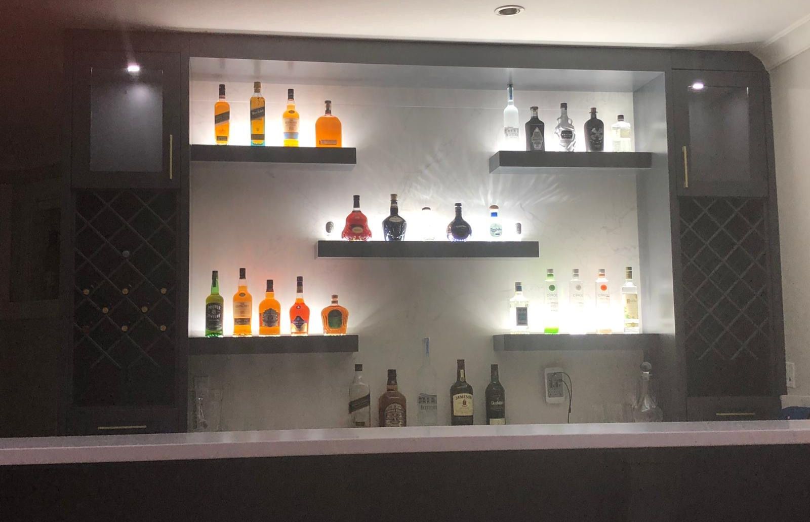 Home bar with backlit floating shelves and built-in wine racks